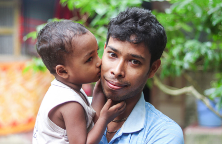 Image shows a young asian man holding his child.